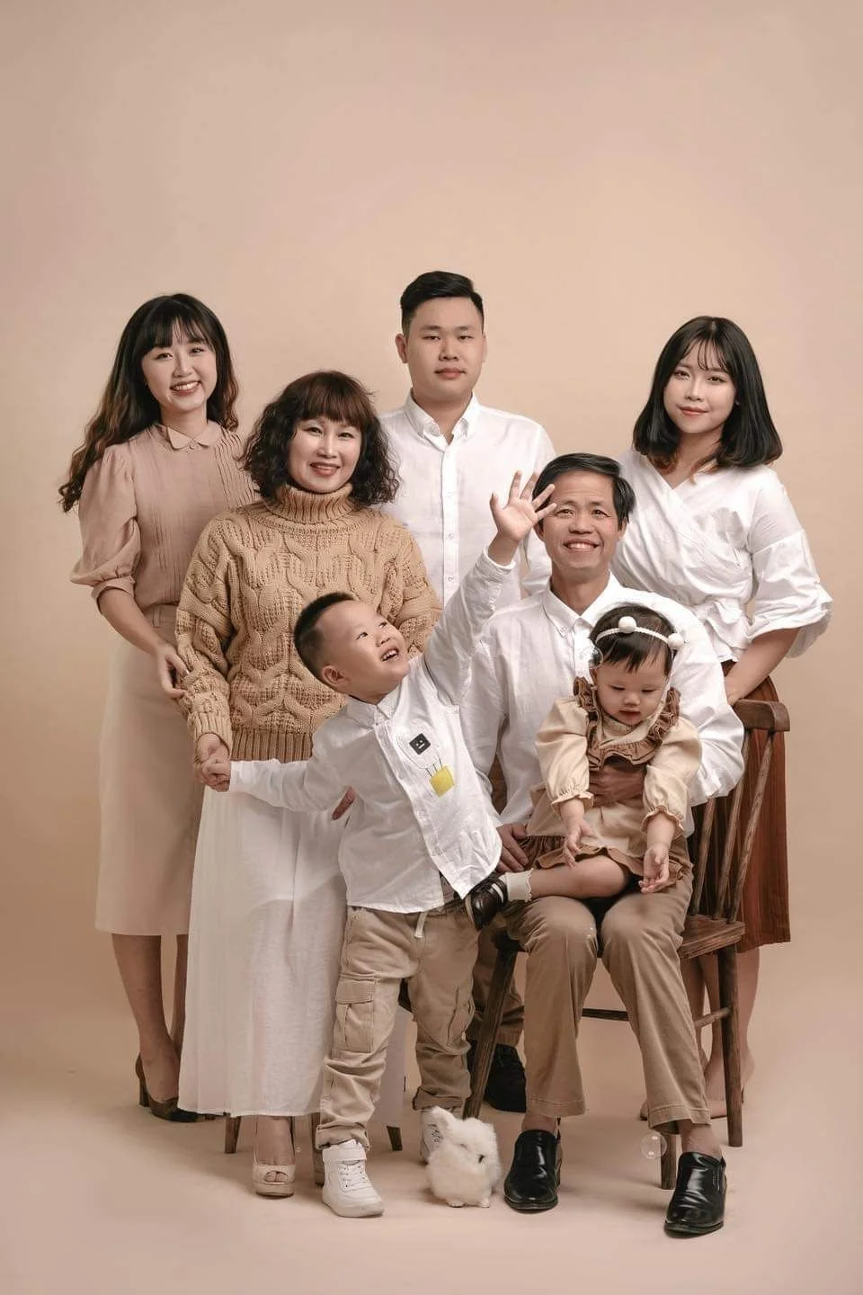 Ảnh gia đình nhiều thế hệ vui vẻ chụp chân dung trong studio với hai em nhỏ và chú chó trắng