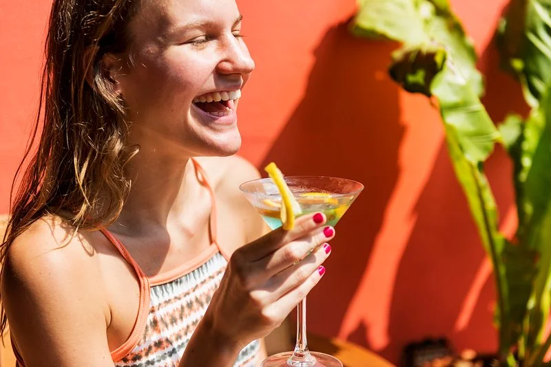 Người phụ nữ mặc bikini cầm ly cocktail trong không gian nhiệt đới rực nắng, gợi cảm giác bikini trên bãi biển